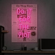 a pink neon sign that says do it for the plot next to a laptop on a desk