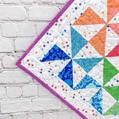 a colorful quilt hanging on a brick wall