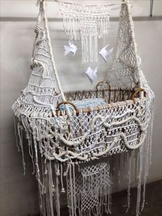 a baby crib made out of macrame and white yarn with paper cranes hanging from it