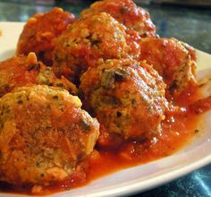 meatballs covered in marinara sauce on a white plate