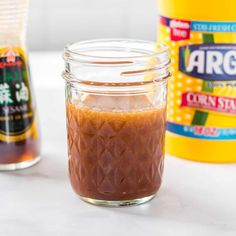 two jars filled with peanut butter sitting on top of a counter next to other ingredients