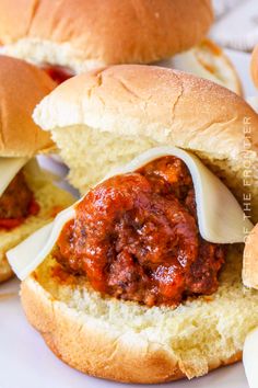 two meatball sandwiches on buns with cheese and tomato sauce in between the buns