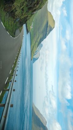 an aerial view of a road with a waterfall in the middle and blue water on both sides