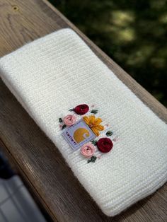 a white towel with flowers on it sitting on top of a wooden table