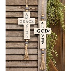 two wooden crosses hanging from the side of a building with words on them and tassels