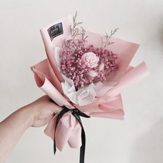 a hand holding a bouquet of pink flowers