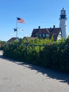 an american flag flying in front of a lighthouse