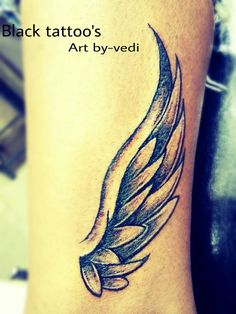 a tattoo on the leg of a person with a black and grey feather design on it