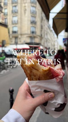 a person holding up a piece of food with the words where to eat in paris