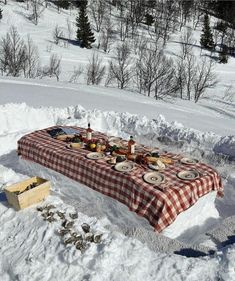 a picnic table set up in the snow with plates and food laid out on it