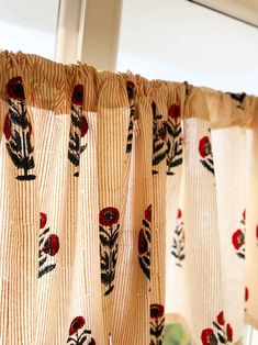 a curtain with red flowers on it hanging in front of a window