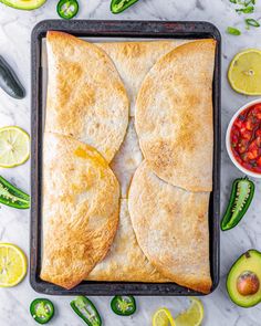 two pita breads on a baking sheet with sliced jalapenos and salsa