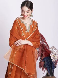 Indulge in timeless elegance with this rust kurta set. Its luxurious silk kurta is accentuated with delicate zari embroidery, while the cotton silk pants and organza dupatta are finished with exquisite gota work. A truly regal ensemble to make you feel like royalty. No. of pieces - 3 piece set. Fabric - Silk, Cotton Silk and Oraganza. Color - Rust. Kurta Length - 44 inches. Washing Instructions - Dry Clean. Rust Color Dress, Zari Embroidery, Gota Work, Palazzo Suit, Silk Kurta, Organza Dupatta, Silk Pants, Punjabi Suits, Fabric Silk