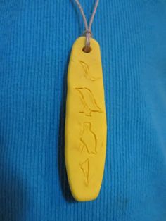 a yellow necklace with writing on it and a bird in the middle is attached to a blue sweater