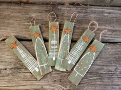 four wooden christmas tree ornaments hanging from twine on wood planks with star decorations