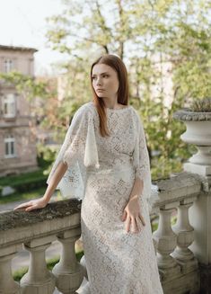 a woman in a white dress standing on a balcony