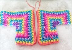 two crocheted sweaters sitting next to each other