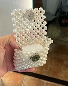 a hand holding a cell phone case made out of pearls