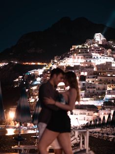 a man and woman standing next to each other in front of a city at night