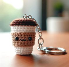 a crocheted coffee cup keychain sitting on top of a wooden table