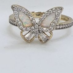 an opal and diamond butterfly ring on a white surface with diamonds surrounding the band