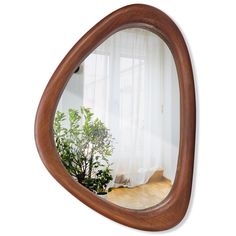 a wooden mirror reflecting a room with white curtains on the window sill and a potted plant