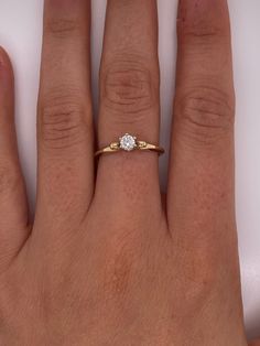 a woman's hand with a diamond ring on top of her left hand,