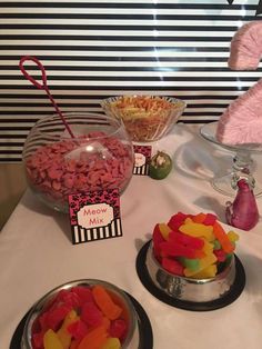 a table topped with bowls filled with candy and candies next to a pink flamingo