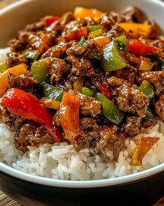 a white bowl filled with rice and meat on top of a wooden table next to a fork