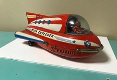 a red and white toy airplane on top of a blue table next to a wall