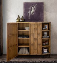 a wooden cabinet with two vases on top of it next to a large window