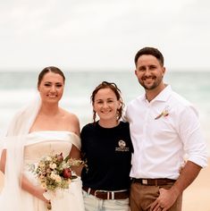 two men and a woman standing on the beach