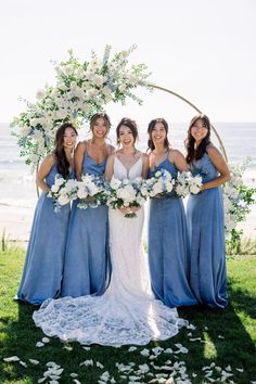 the bride and her bridesmaids pose with their bouquets in front of the ocean