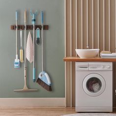 a washer and dryer in a room next to a wall with brooms