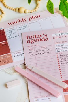 a pink planner and pen on top of a table