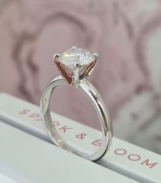 a close up of a diamond ring on top of a table with a sign in the background