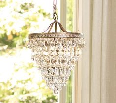 a chandelier hanging from the ceiling in front of a window with trees outside