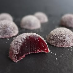 powdered sugar covered pastries sit on a black surface with white sprinkles