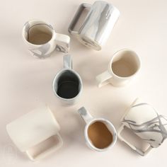 five coffee mugs sitting on top of a white table next to each other with different shapes and sizes