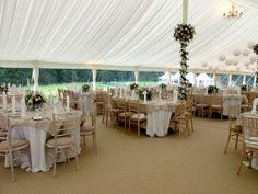 tables and chairs are set up in a large tent for an event with white linens