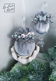 two silver vases with flowers in them sitting on top of a table next to christmas decorations