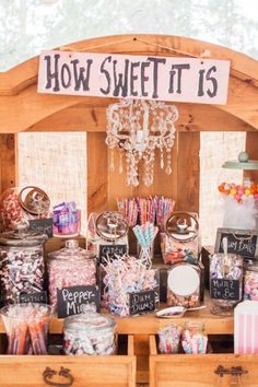 a wooden table topped with lots of candies and candy bar items next to a sign that says how sweet it is