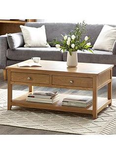 a living room with a couch, coffee table and flowers in vase on the floor