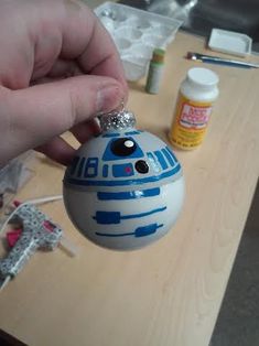 a hand holding a star wars ornament on top of a wooden table next to other items