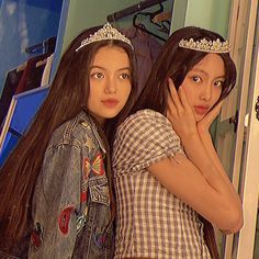 two young women standing next to each other in front of a mirror wearing tiaras