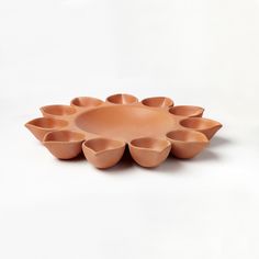 an orange bowl with six bowls in it on a white surface, the top half is shaped like a flower