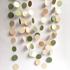 some paper circles hanging from the ceiling in front of a white wall with green and brown decorations on it