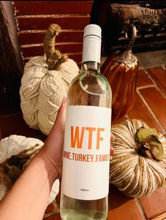 a hand holding a bottle of wftf wine next to pumpkins