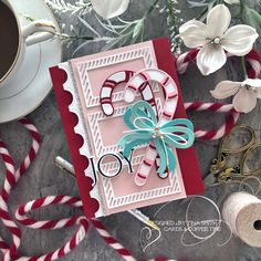 a card with some candy canes and flowers on the table next to yarn, scissors and other crafting supplies