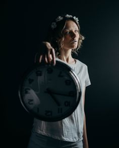 a woman holding a clock in the dark